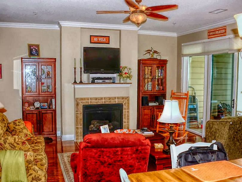 Living room with hardwood flooring, fireplace, ceiling fans, crown molding and more